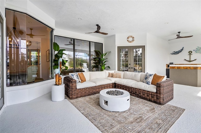 carpeted living room with ceiling fan, french doors, and a textured ceiling