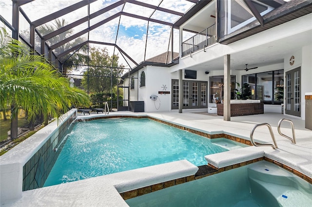 view of pool with glass enclosure, ceiling fan, a patio area, pool water feature, and an in ground hot tub