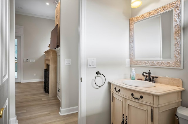 bathroom featuring toilet, vanity, crown molding, and hardwood / wood-style flooring