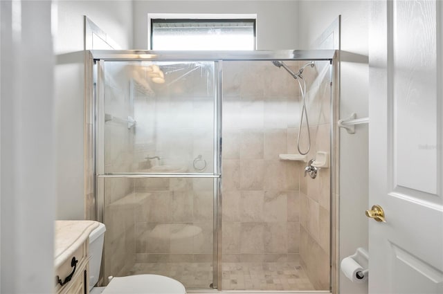 bathroom featuring toilet and a shower with door