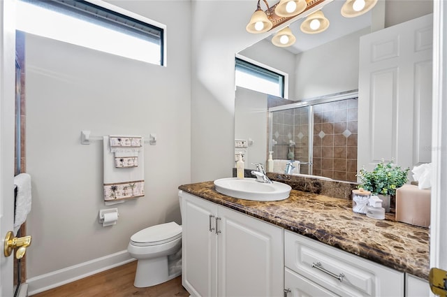 bathroom with toilet, vanity, a shower with door, and hardwood / wood-style flooring