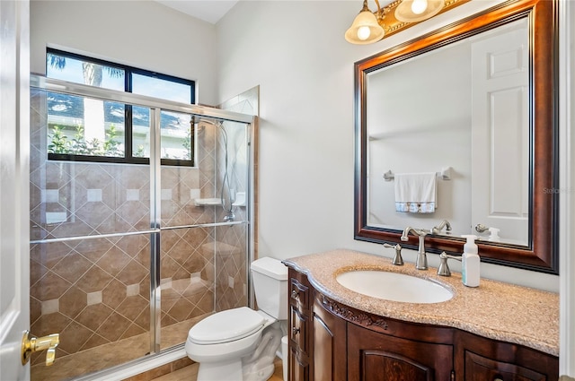 bathroom featuring toilet, vanity, and a shower with door