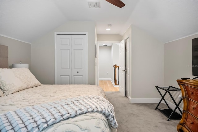 carpeted bedroom with ceiling fan, a closet, and vaulted ceiling