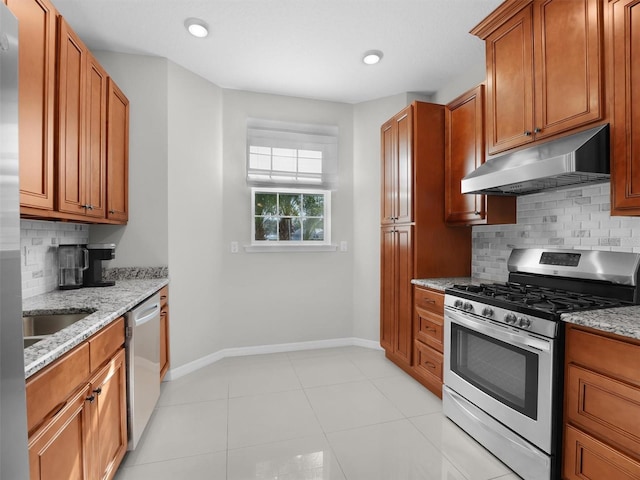 kitchen with light tile patterned flooring, sink, stainless steel appliances, light stone countertops, and backsplash