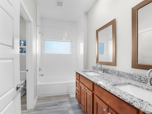 full bathroom featuring tiled shower / bath, vanity, and toilet