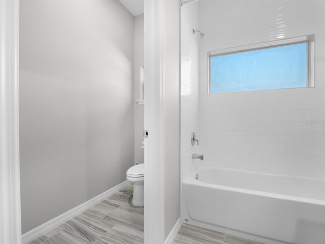 bathroom featuring tiled shower / bath combo and toilet