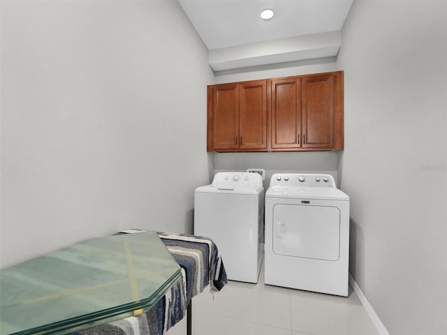 laundry room with washing machine and dryer, cabinets, and light tile patterned flooring