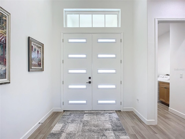 entrance foyer featuring light wood-type flooring and a towering ceiling