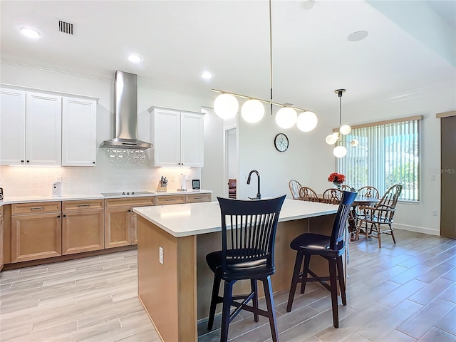 kitchen with white cabinetry, an island with sink, ventilation hood, a breakfast bar area, and hanging light fixtures