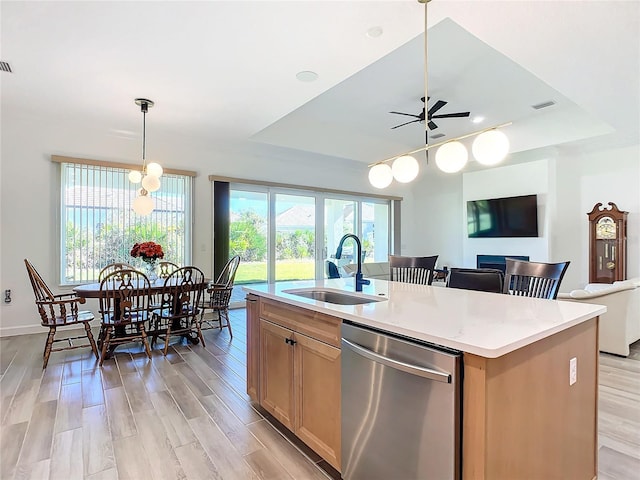 kitchen with a center island with sink, ceiling fan, pendant lighting, stainless steel dishwasher, and sink