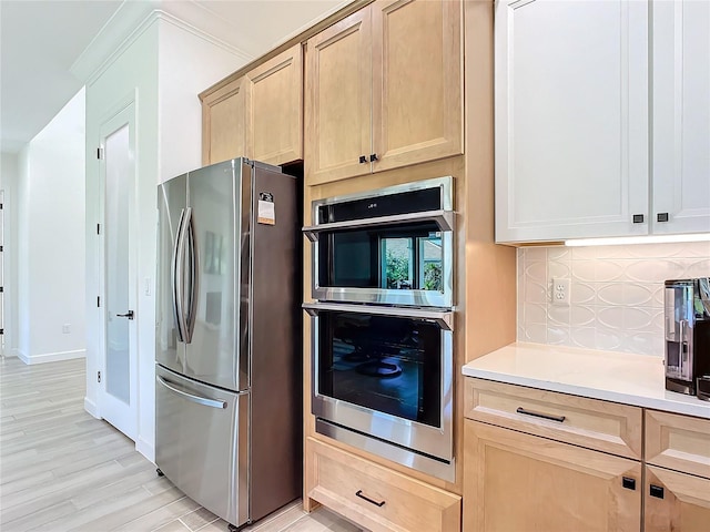 kitchen featuring light brown cabinetry, light hardwood / wood-style flooring, stainless steel appliances, and tasteful backsplash