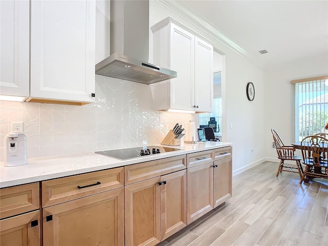 kitchen featuring wall chimney exhaust hood, white cabinetry, black electric stovetop, decorative backsplash, and light hardwood / wood-style flooring