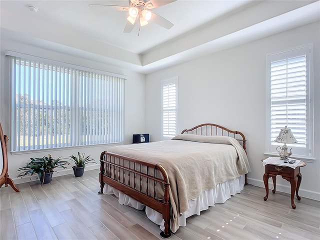 bedroom featuring ceiling fan, multiple windows, and light hardwood / wood-style flooring