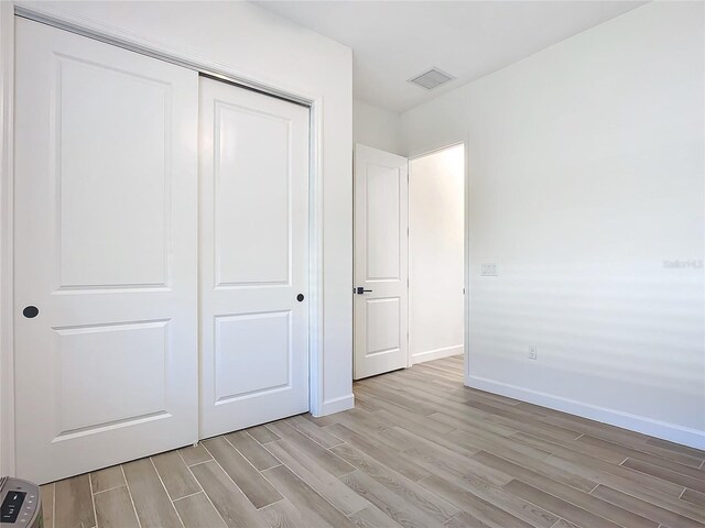 unfurnished bedroom with a closet and light hardwood / wood-style floors