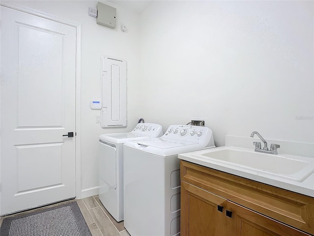 clothes washing area with washing machine and dryer, sink, and cabinets