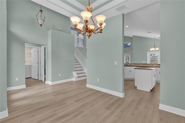 unfurnished living room featuring sink, light hardwood / wood-style flooring, a notable chandelier, and vaulted ceiling