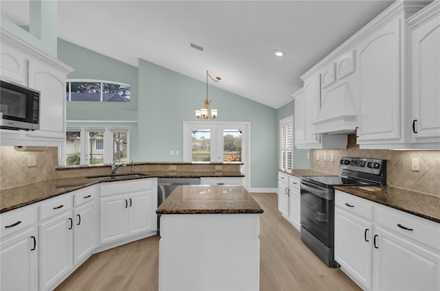 kitchen featuring lofted ceiling, appliances with stainless steel finishes, white cabinetry, and a center island