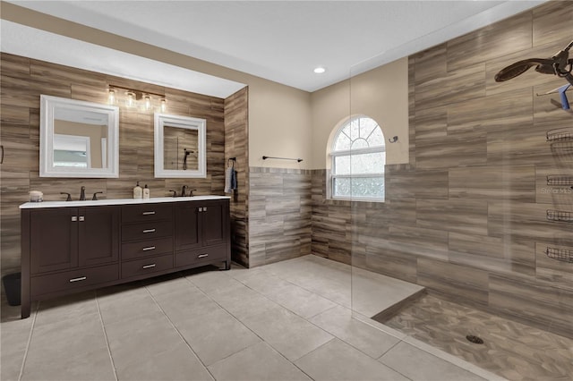 bathroom featuring tile walls, vanity, a tile shower, and tile patterned flooring