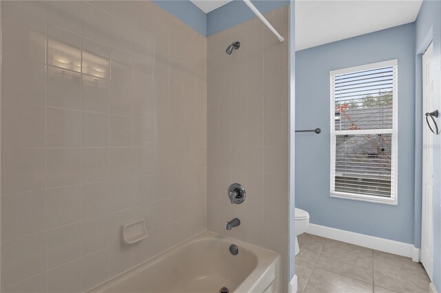 bathroom with toilet, tiled shower / bath, and tile patterned flooring