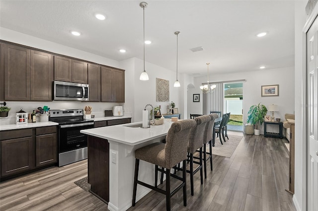 kitchen featuring appliances with stainless steel finishes, sink, a kitchen breakfast bar, hanging light fixtures, and a kitchen island with sink