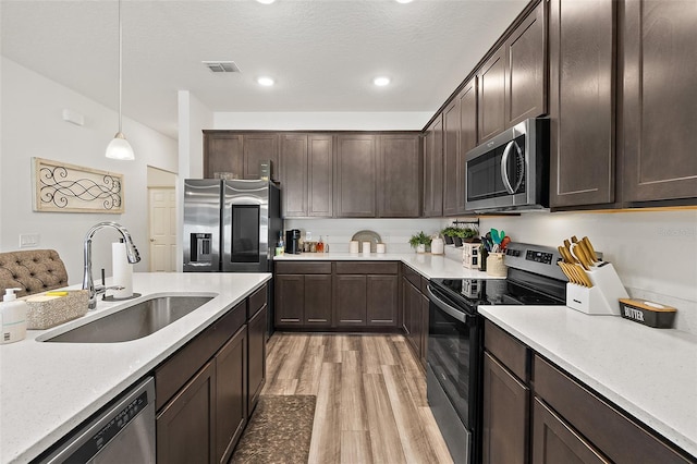 kitchen featuring dark brown cabinetry, appliances with stainless steel finishes, sink, and pendant lighting