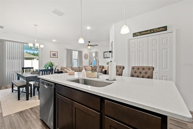 kitchen featuring ceiling fan with notable chandelier, dishwasher, decorative light fixtures, sink, and a kitchen island with sink