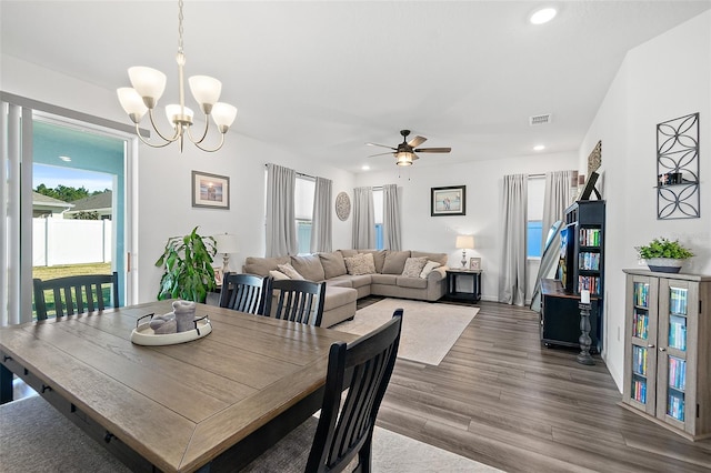 dining area with ceiling fan with notable chandelier and hardwood / wood-style flooring