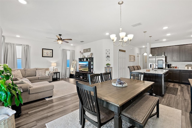 dining space with ceiling fan with notable chandelier, hardwood / wood-style flooring, and sink