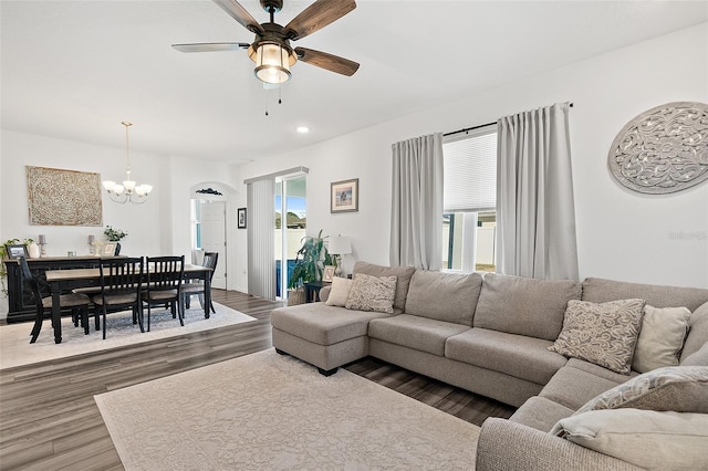 living room with ceiling fan with notable chandelier, a wealth of natural light, and dark hardwood / wood-style flooring