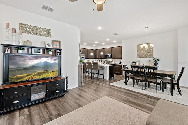 living room featuring ceiling fan with notable chandelier and hardwood / wood-style flooring