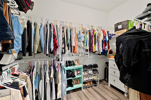 walk in closet with light hardwood / wood-style floors