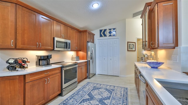 kitchen with lofted ceiling, stainless steel appliances, and a textured ceiling