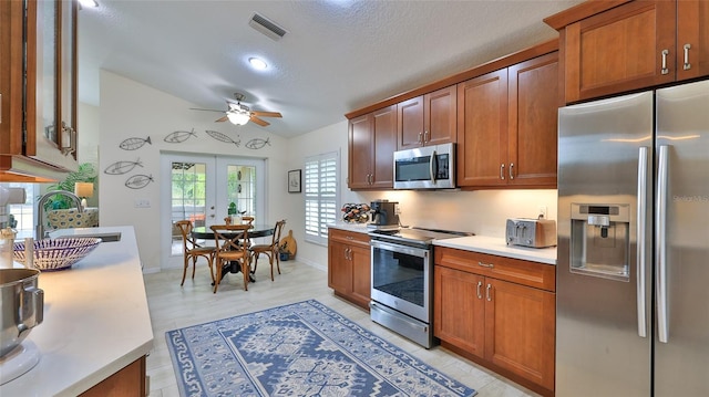 kitchen with lofted ceiling, stainless steel appliances, french doors, sink, and ceiling fan