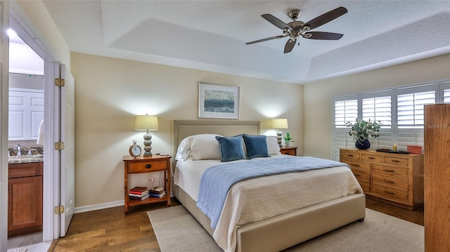 bedroom with ceiling fan, hardwood / wood-style floors, a tray ceiling, and a textured ceiling