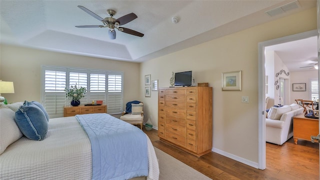 bedroom with ceiling fan, hardwood / wood-style floors, and a raised ceiling