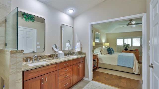 bathroom with hardwood / wood-style flooring, ceiling fan, vaulted ceiling, a textured ceiling, and vanity