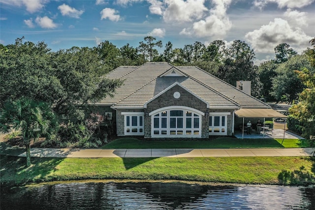 rear view of house with a water view, french doors, and a yard