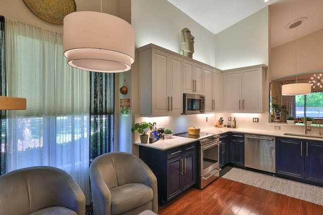 kitchen with tasteful backsplash, pendant lighting, sink, appliances with stainless steel finishes, and high vaulted ceiling