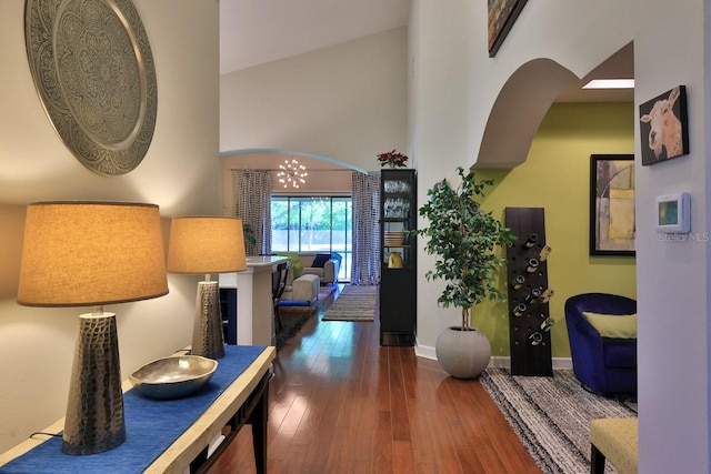 hallway featuring a chandelier, dark hardwood / wood-style floors, and high vaulted ceiling