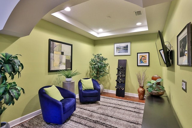 living area with hardwood / wood-style flooring and a raised ceiling