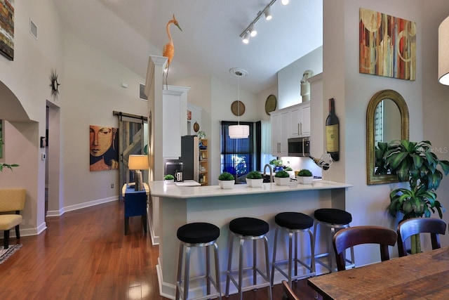 kitchen with pendant lighting, kitchen peninsula, white cabinetry, a kitchen breakfast bar, and dark hardwood / wood-style flooring