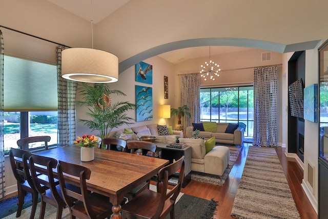 dining space featuring lofted ceiling, dark hardwood / wood-style flooring, and an inviting chandelier