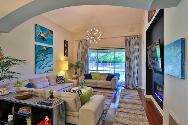 living room with wood-type flooring, a notable chandelier, and vaulted ceiling