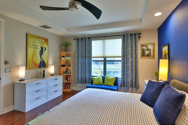 bedroom with a raised ceiling, ceiling fan, and dark hardwood / wood-style floors