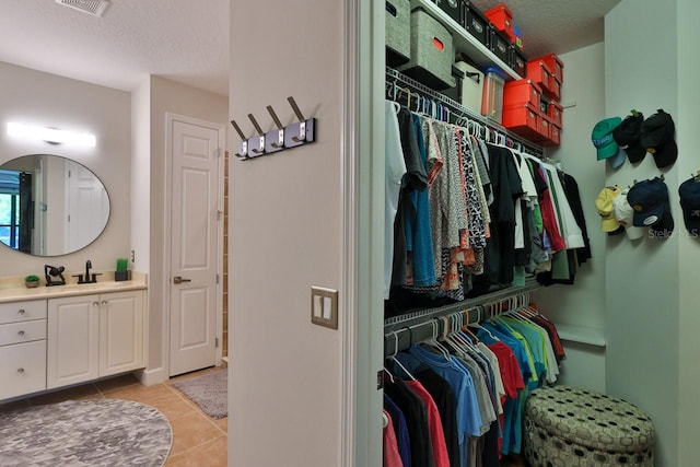 spacious closet featuring sink and light tile patterned floors