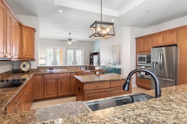 kitchen with ceiling fan, a kitchen island, sink, hanging light fixtures, and stainless steel appliances