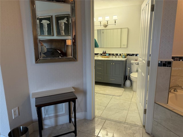 bathroom with toilet, vanity, tile patterned flooring, and a relaxing tiled tub