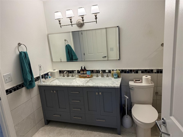 bathroom with toilet, vanity, tile walls, and tile patterned floors