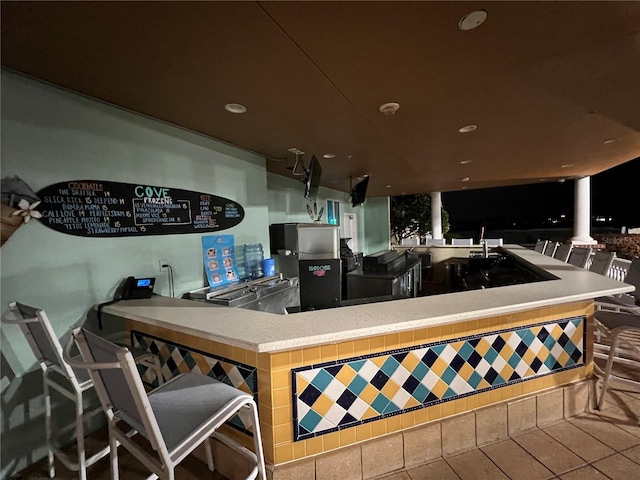 kitchen featuring tile patterned floors, kitchen peninsula, and a kitchen bar