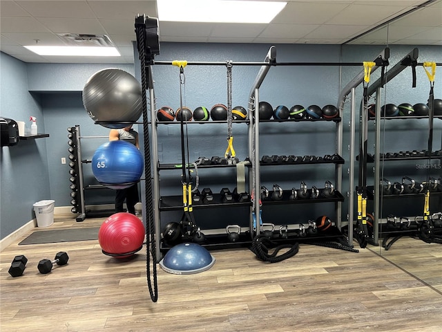 workout area with a paneled ceiling and wood-type flooring